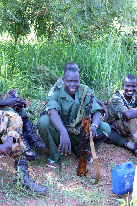 a group of men are sitting down with guns