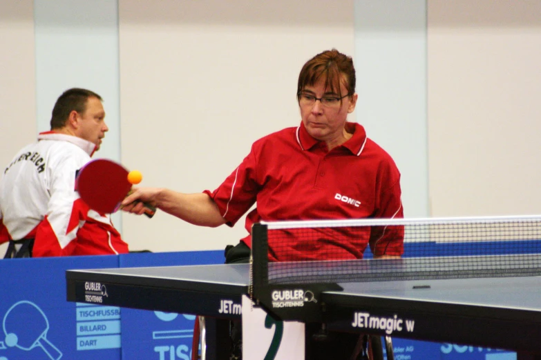 two men holding ping pong paddles and a ball on top of a table