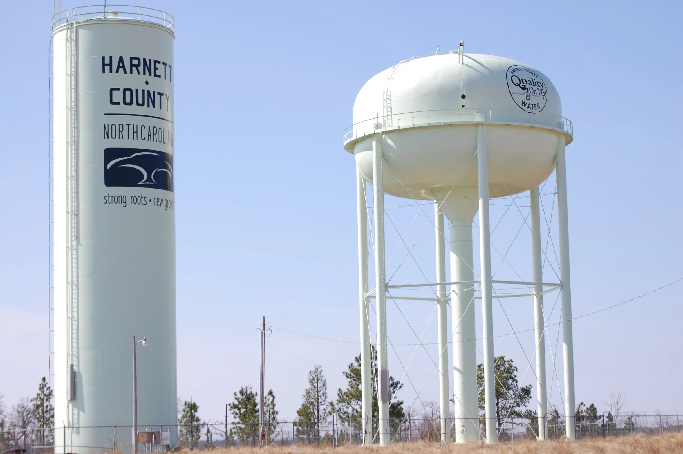 a white water tower next to a metal water barrel