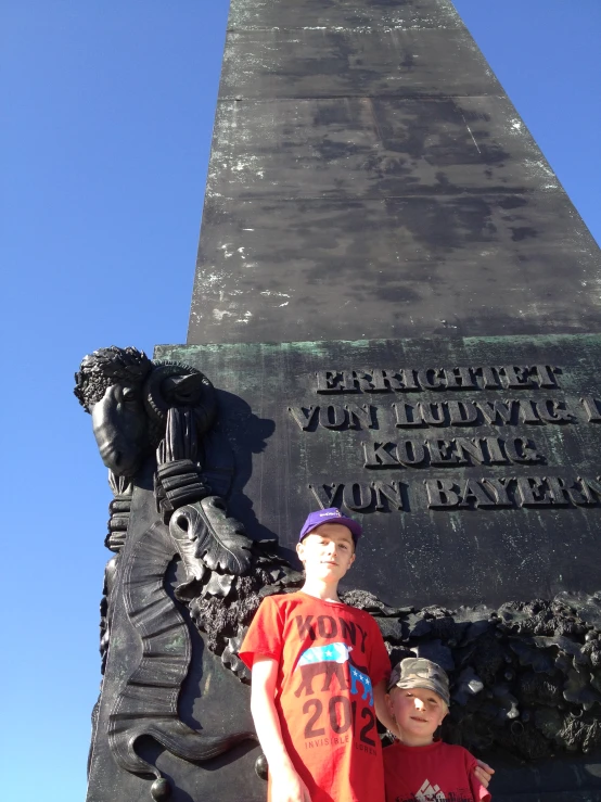 two boys stand in front of a monument