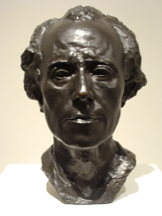 a head statue is sitting on a white pedestal