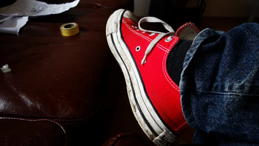 the feet are resting on a leather sofa