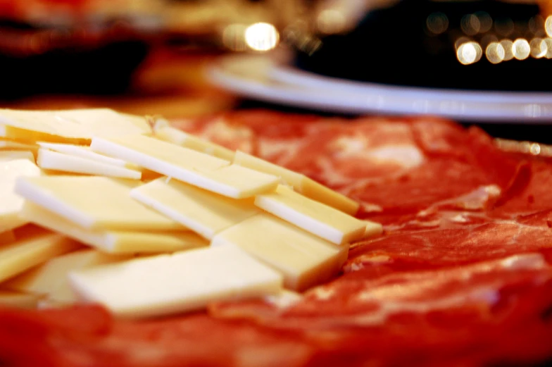 cheese cubes and meat slices sitting on a plate