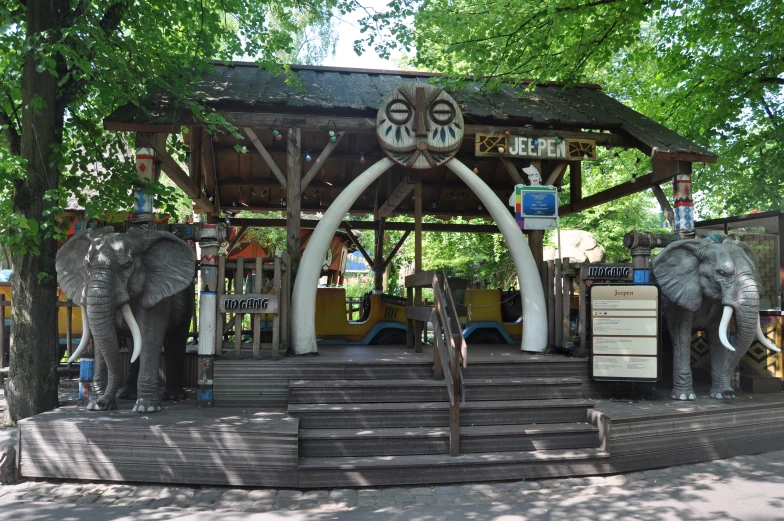 three elephants are sitting under a structure at a park