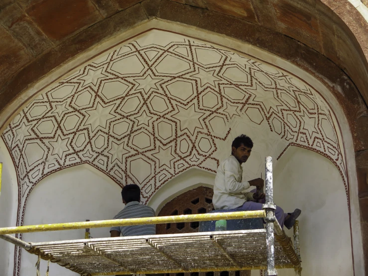 a group of men work on an ornate wall