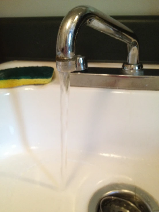 a faucet running water over a sink that has been painted yellow and blue