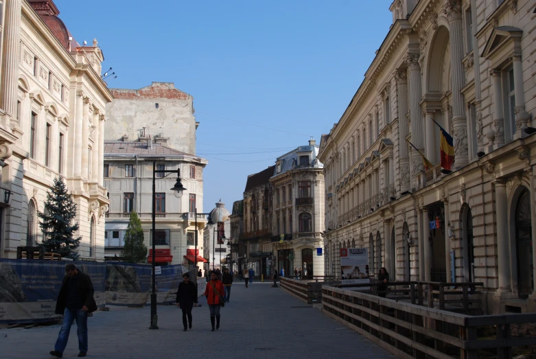 people walking in an old town with a blue sky