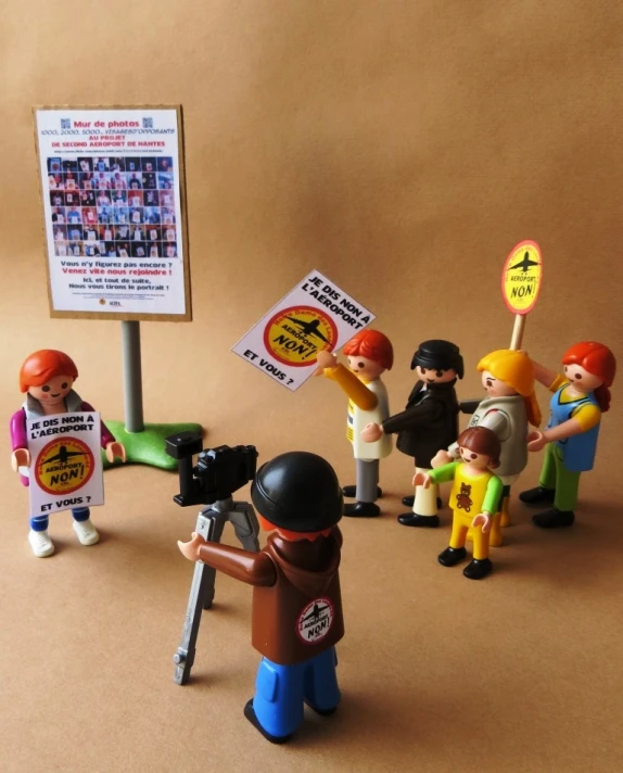 a group of miniature people holding protest signs and pictures