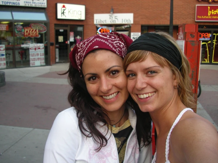 two young women posing for the camera on the street