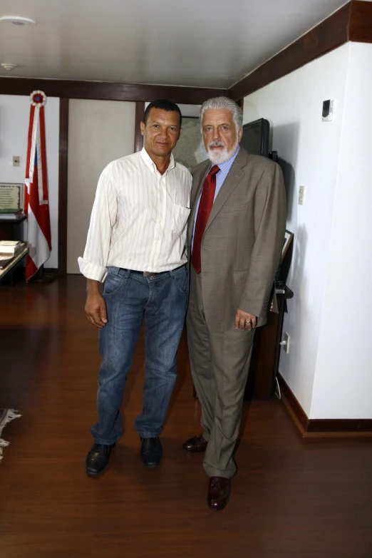 two men standing next to each other near a room with flags on it