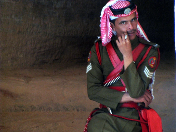 the man wearing the green uniform is smoking a cigarette