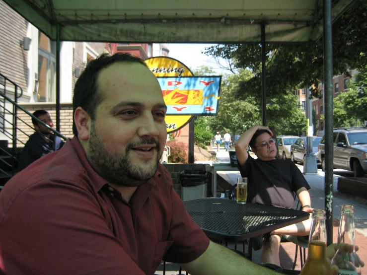 a man sitting at an outdoor restaurant eating food