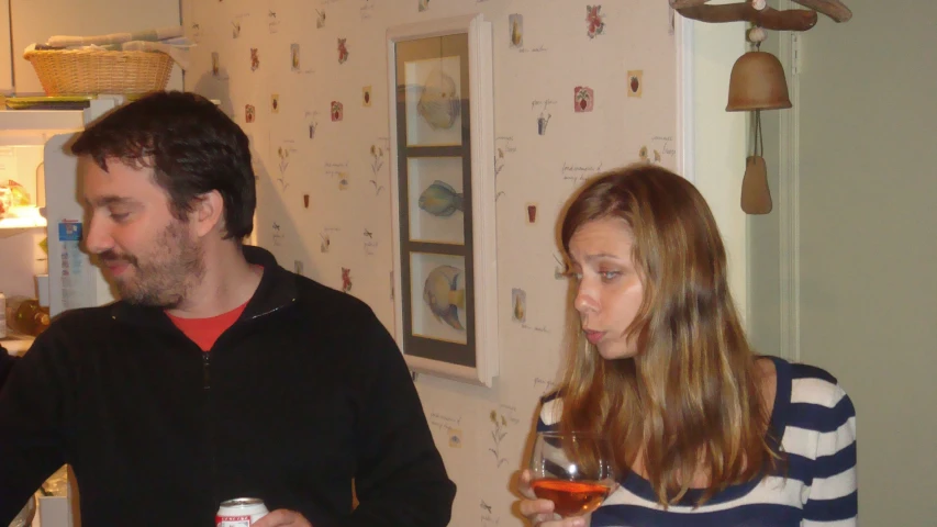 the man and woman are standing in a kitchen holding glasses