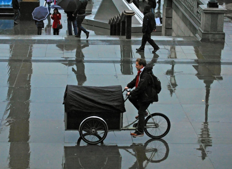 a woman riding on a bike that is pulling a cart