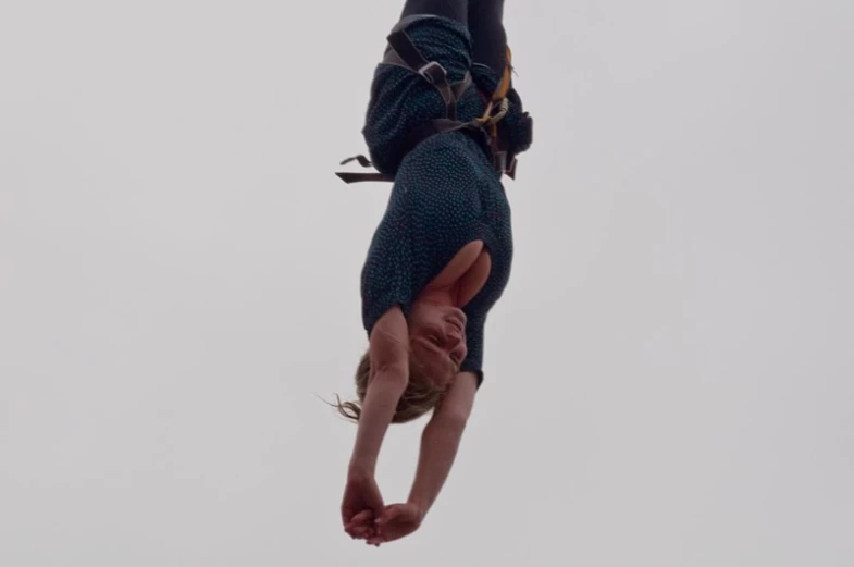 a woman standing on her back while dangling from the side