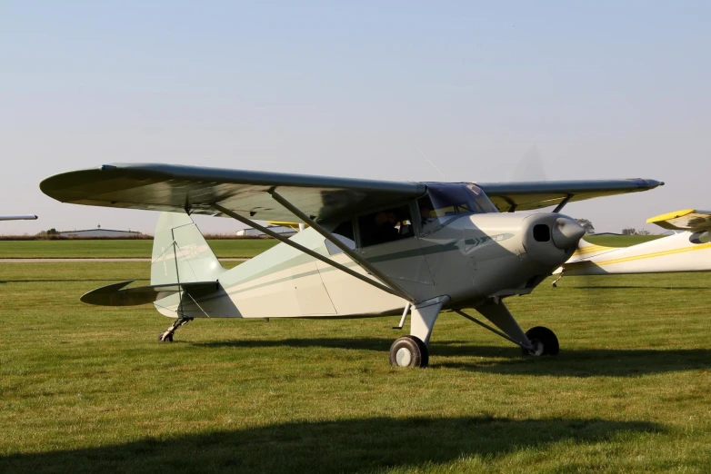 a small, light blue propeller plane on a green grass field