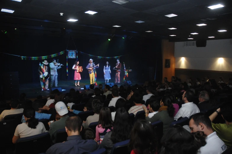 a crowd watches a stage that has four men on it