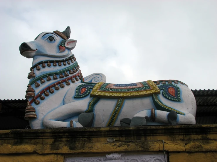 a large white cow statue is on top of a building