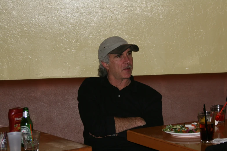 a man in black shirt and hat sitting in a booth