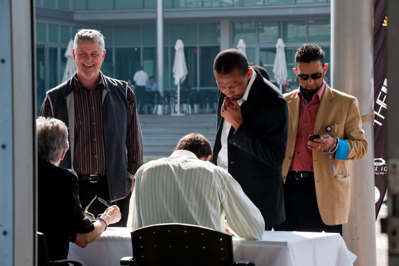 some men are standing around a white table