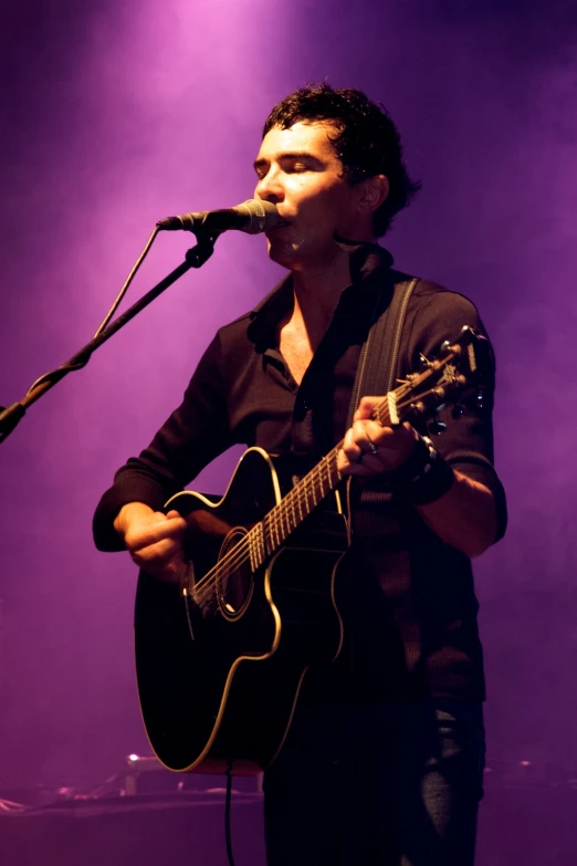 a man standing on top of a stage holding a guitar