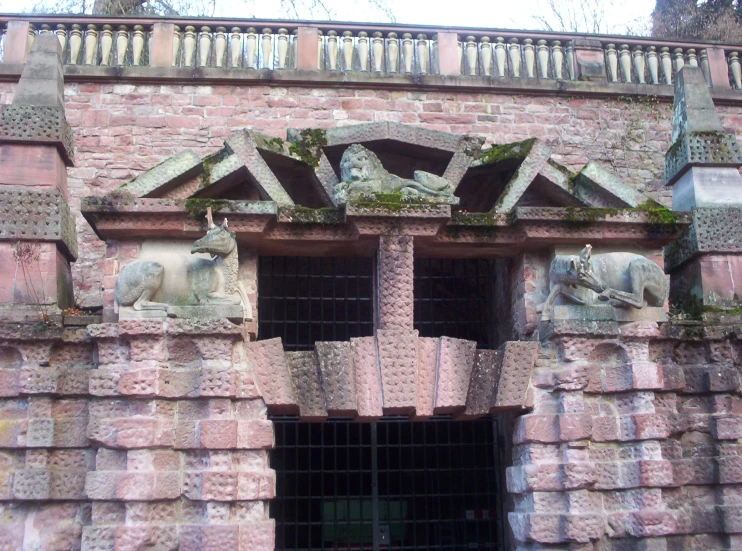 some stone statues above a door and brick building