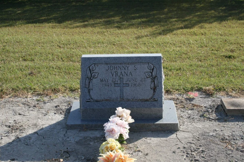 a tombstone with pink and orange flowers placed on it