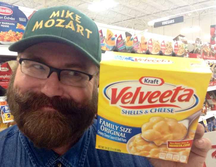 a man with a beard holding up a box of cheetos