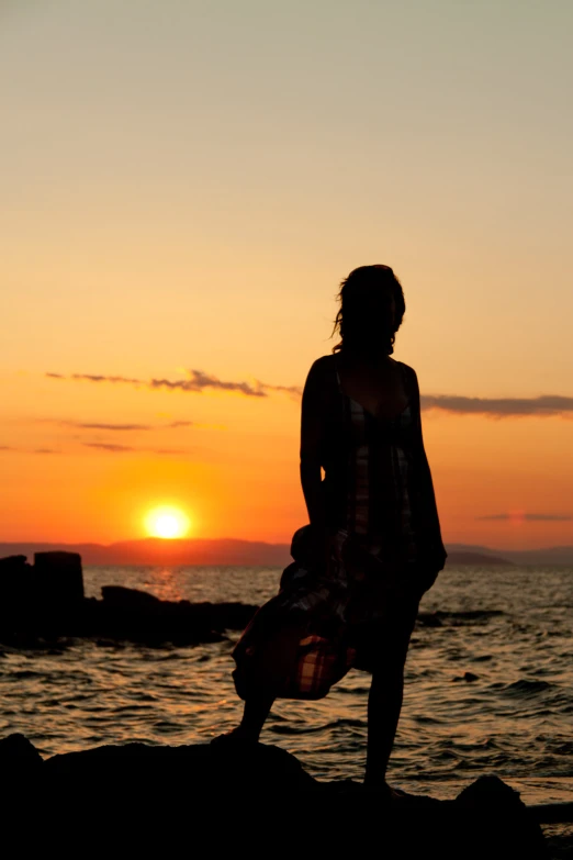 a person with a surfboard in hand is silhouetted against a sunset
