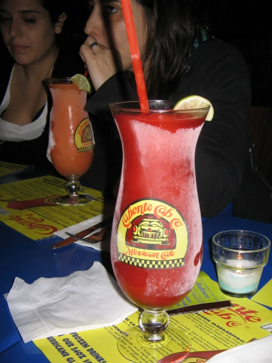 a red drink with a yellow straw sitting on a table next to a yellow napkin