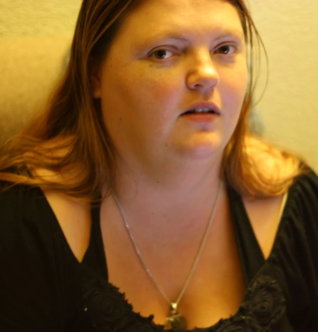 a woman with brown hair wearing a black shirt and necklace