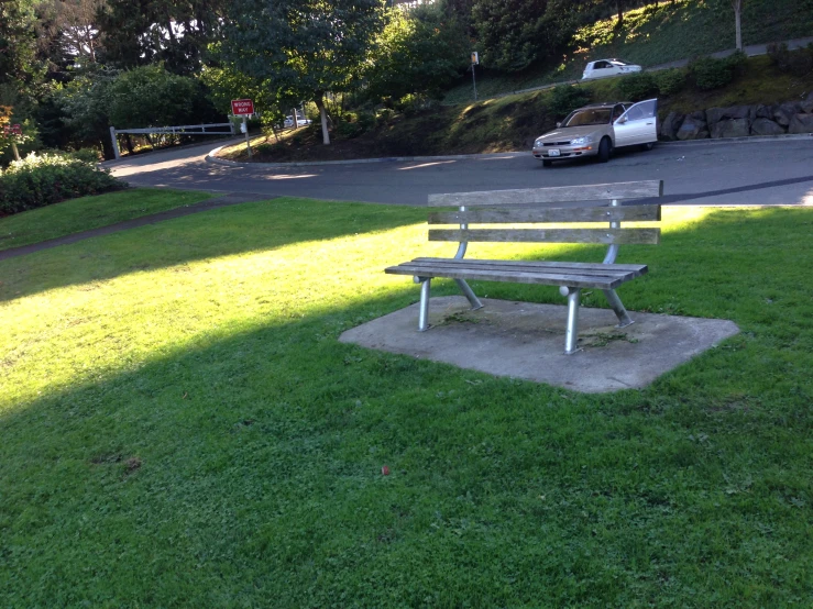 an empty bench in the grass in front of a road