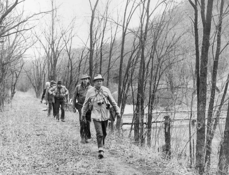 men walk down a dirt path in the woods