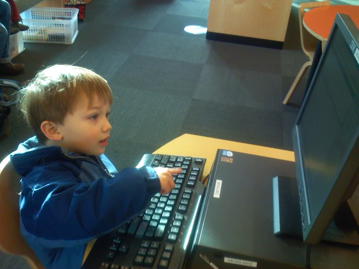 a little boy sitting in front of a computer on top of a desk