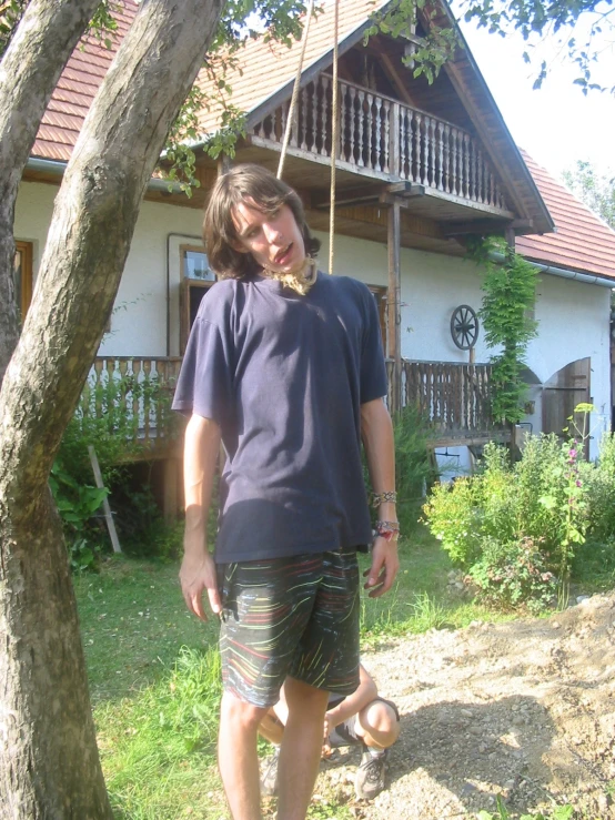 man standing underneath a tree with one eye closed