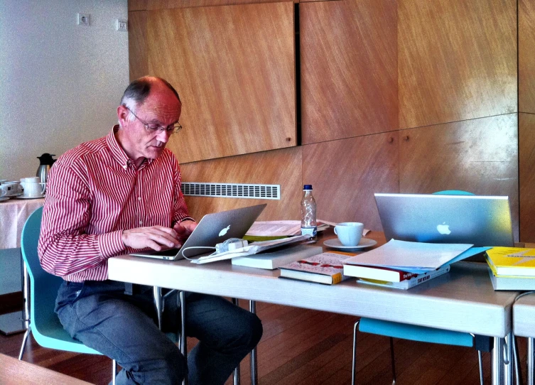 a man sitting at a desk with a laptop in his hand