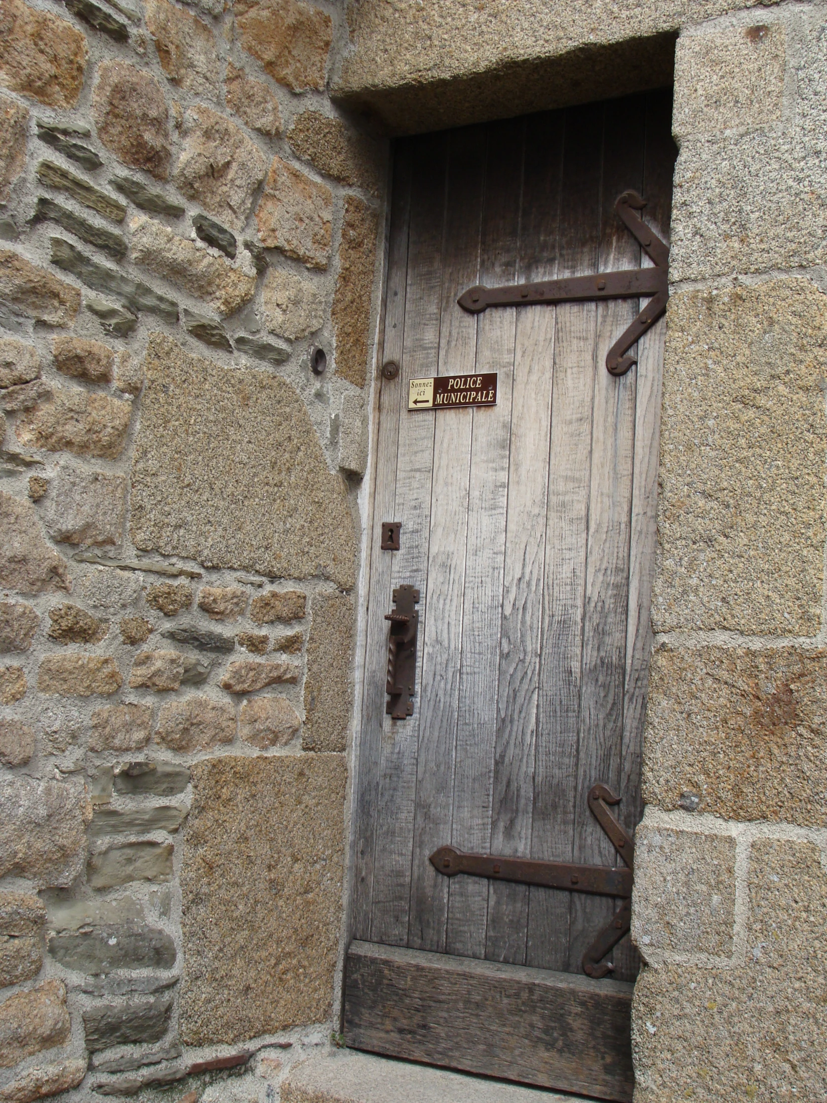 the wooden door to the stone building is open