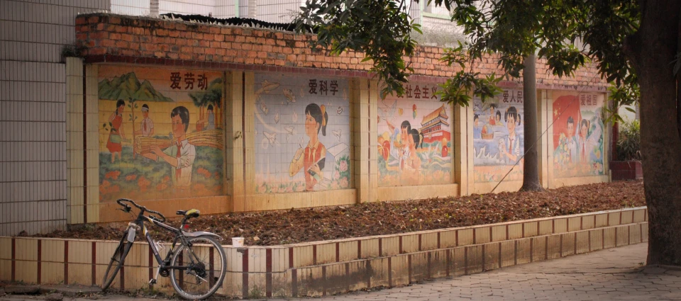 bicycles are parked outside a building with asian paintings on the walls