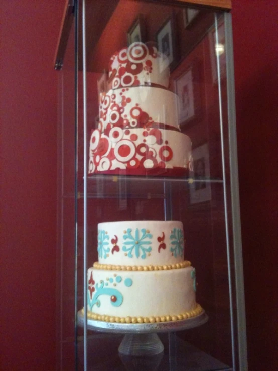 three layered cake in a glass case with wood stand