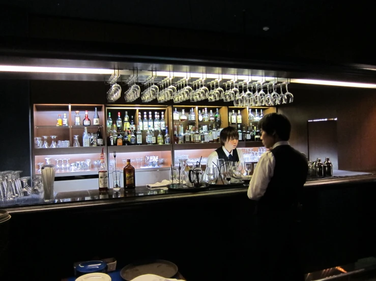 two men in front of a bar filled with bottles