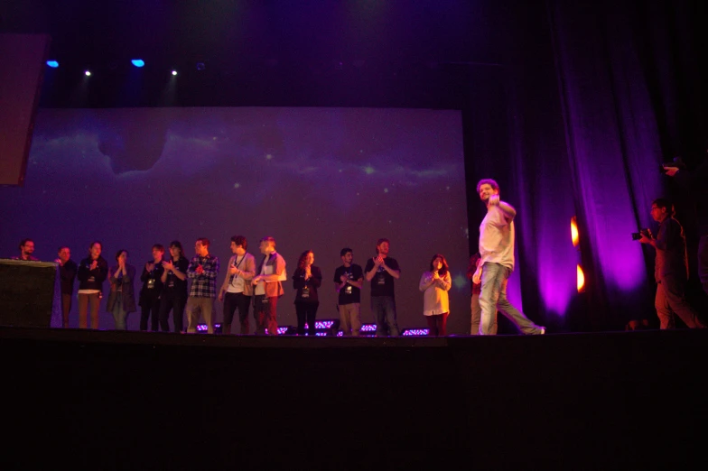 a man standing on top of a stage surrounded by people