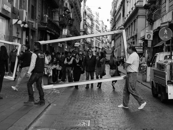 two men carrying pos on each of them on the street