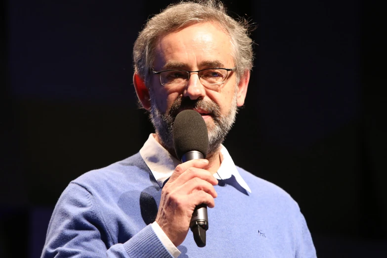 a man with grey hair standing next to a microphone