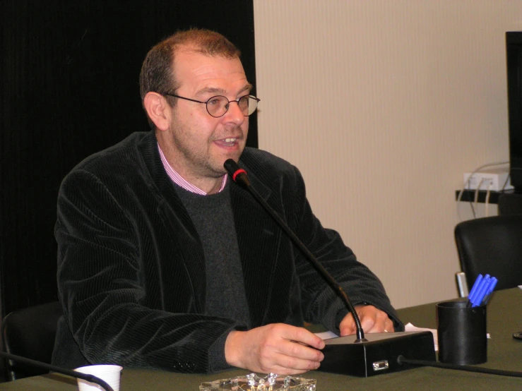 a man is sitting at a desk with a microphone