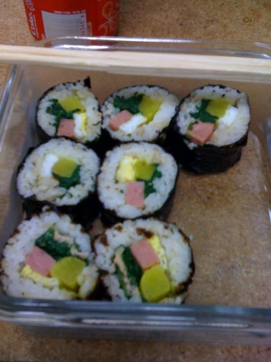 several pieces of sushi sitting in a dish, in front of a drink bottle