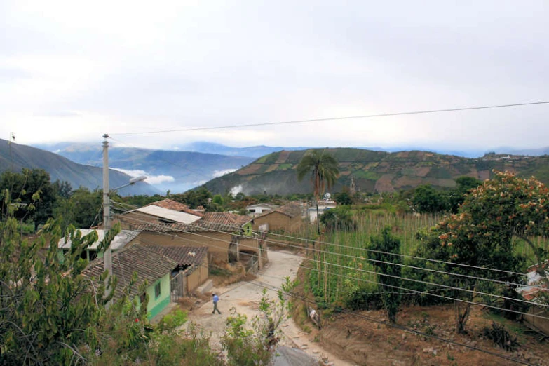 the mountains are behind small houses and a few people