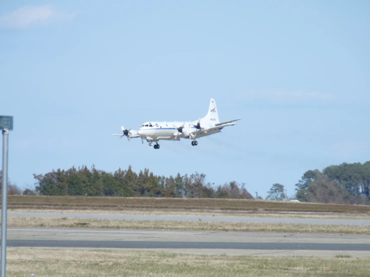 a large jetliner flying through a blue sky above grass and trees