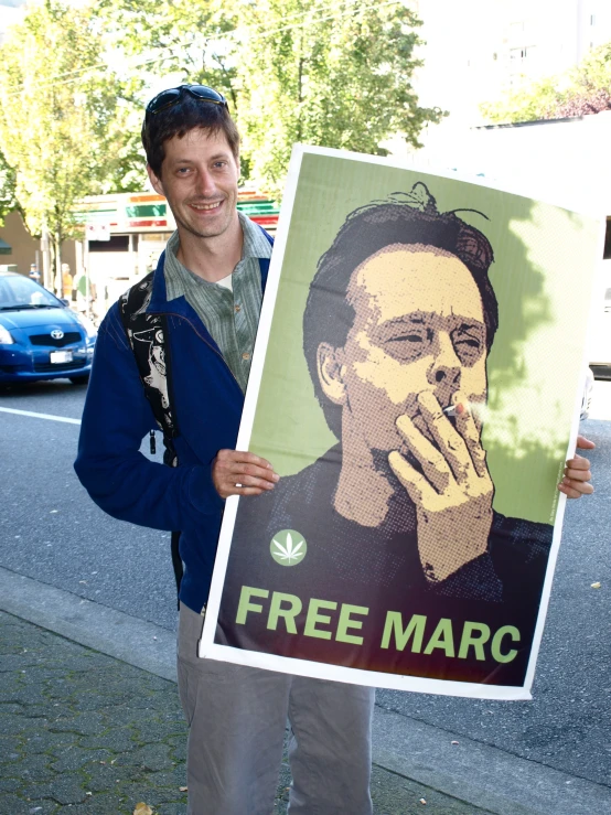 a man standing on the side of the road holding a poster