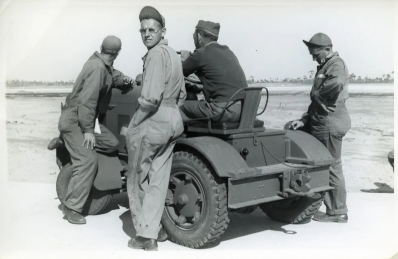 men with hats stand next to an old jeep