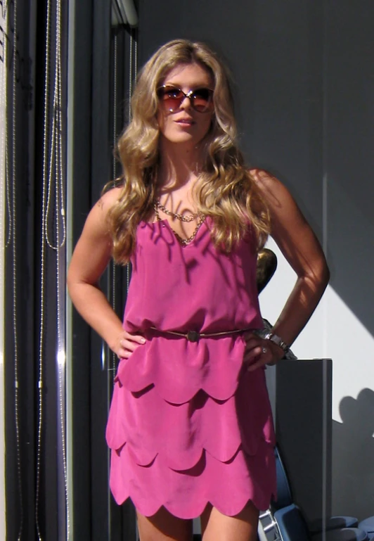 woman in a pink dress standing next to a building